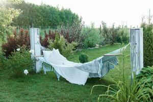 A hammock with pillows and a blanket on the street in the courtyard of a village house. A place to relax in the country. The concept of summer, trips to the country. photo