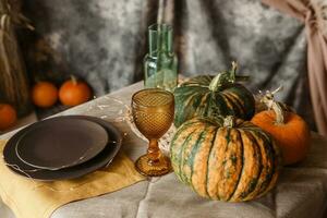 Autumn interior. A table covered with dishes, pumpkins, a relaxed composition of Japanese pampas grass. Interior in the photo Studio. decorated autumn table