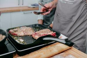 Cocinando filetes en un cacerola. Cocinando carne de vaca a el culinario Maestro clase. el manos de el cocinero en negro guantes. foto