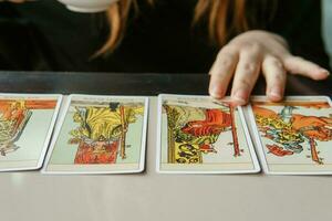 TVER, RUSSIA - FEBRUARY 11, 2023. Tarot cards, Tarot card divination, esoteric background. A woman makes a layout on the cards at the table. Divination, predictions on tarot cards. photo