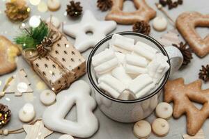 A cup of cocoa with marshmallows and New Year's gingerbread and a gift on the table, bokeh lights in the foreground. The concept of desserts and drinks during the Christmas holidays. photo