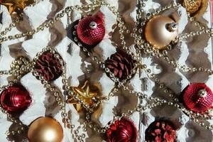 Christmas tree toys in the egg tray on a red background. Top view. The concept of New Year's holidays and Christmas. Red and gold colors. photo