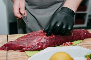 Raw beef meat for steak preparation. Raw beef sliced, preparation of meat for cooking steak at the culinary master class. Raw meat on a black plate. photo