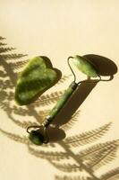 Jade Gua sha scraper and facial massager on beige background. photo