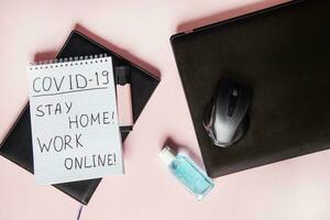 Top view of a desktop with laptops, a marker, and a laptop. Text Covid-19, stay at home, WORK ONLINE. Work from home using an online device, protection from coronavirus during the quarantine period. photo