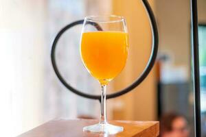 Orange juice in a wine glass is placed on the table in the kitchen. photo