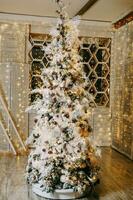 hermosamente decorado Navidad árbol y un montón de brillante guirnaldas y ligero bombillas preparando para el Navidad fiesta a hogar. foto