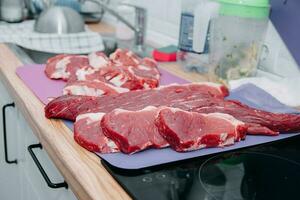 Raw beef meat for steak preparation. Raw beef sliced, preparation of meat for cooking steak at the culinary master class. Raw meat on a black plate. photo