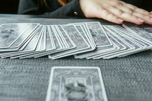 TVER, RUSSIA - FEBRUARY 11, 2023. Tarot cards, Tarot card divination, esoteric background. A woman makes a layout on the cards at the table. Divination, predictions on tarot cards. photo