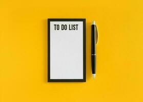 White sheet with to do list phrase and black pen on yellow background. Stock photo. photo