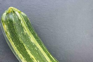 Fresh green striped zucchini on a gray background photo