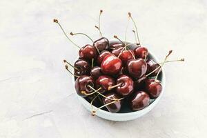 Fresh ripe cherries in bowl on light gray background photo