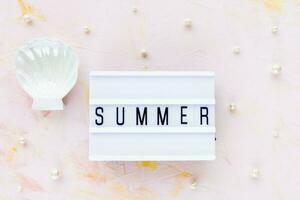 Word SUMMER on pink with white seashell decoration background photo