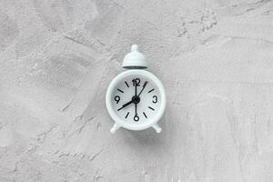 Small vintage alarm clock with bell on gray background photo