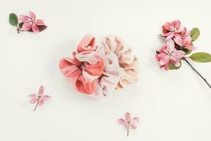 Pink velvet scrunchie and fresh spring red flowers on white background photo