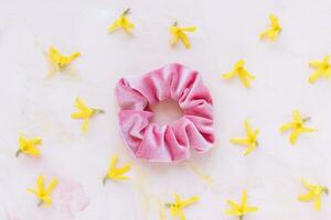 Pink velvet scrunchie and fresh spring yellow flowers photo