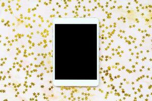 Golden foil stars confetti decoration and tablet photo