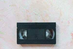 Black vintage VHS video tape on pink background photo