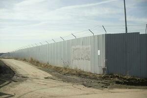 Fence in industrial zone. Road along territory. Passage between fences. photo