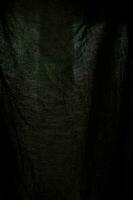 Texture of dark fabric. Fabric to light. Black background. photo