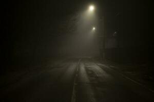 la carretera a noche en niebla. niebla en schosse. débiles ligero en la carretera en oscuro. foto