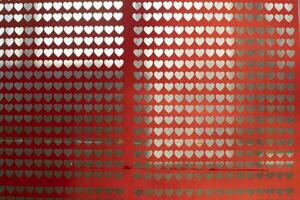 Texture of hearts on glass. Red film with small hearts cut out. Handmade background. photo