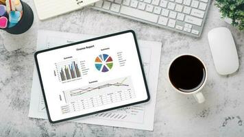 Tablet with charts and reports on office desk workplace. Top view flat lay photo