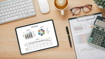 Tablet with charts and reports on office desk workplace. Top view flat lay. photo