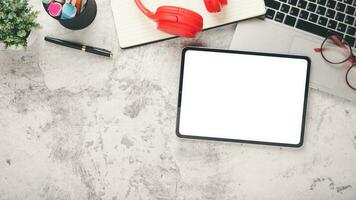 White office desk workplace with blank screen tablet, laptop, eyeglass, headphone, pen and notebook, Top view flat lay with copy space. photo