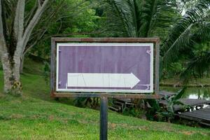 selectively focus on the signboard with the white arrow. signpost template concept in park photo