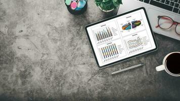 Tablet with charts and reports on office desk workplace. Top view flat lay photo