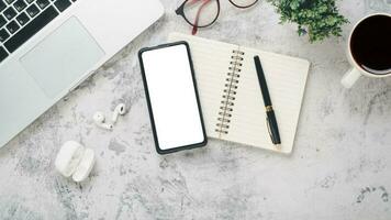 White office desk workplace with blank screen smart phone, laptop, eyeglass, notebook, pen and cup of coffee, Top view flat lay with copy space. photo