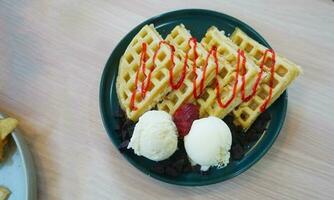 Waffle in tosca plate with sauce strawberry and vanilla ice cream photo