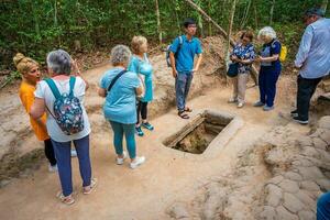 The Cu Chi tunnels. A guide demonstrating how a Vietcong hide into the Tunnel. It's used in Vietnam war. Famous tourist attraction in Vietnam. Stock photo