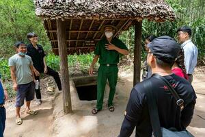 The Cu Chi tunnels. A guide demonstrating how a Vietcong hide into the Tunnel. It's used in Vietnam war. Famous tourist attraction in Vietnam. Stock photo