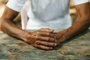 Hands of an old man on the wood table. photo