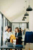 Diverse female fashion designers at work with tailor centimeters on necks and holds tablet and smartphone. independent creative design business. photo