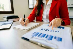 business documents on office desk with laptop and smart phone and graph business diagram and man working in morning light photo