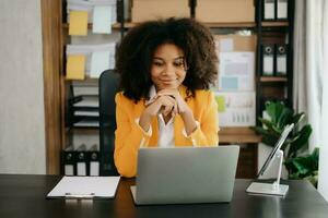 africano mujer de negocios trabajando en el oficina con trabajando bloc, tableta y ordenador portátil documentos foto