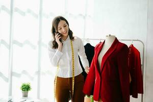 Caucasian young woman on desk in home office of fashion designer and holds tablet, laptop and smartphone. photo