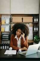 African business woman is stressed, bored, and overthinking from working on a tablet at the office. photo