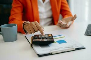 Close up of businesswoman or accountant hand typing laptop working to calculate on desk about cost at home office. photo