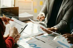 Business documents on office table with smart phone and calculator digital tablet and graph business with social network diagram and two colleagues discussing data working in the office photo
