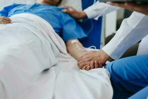 Female doctor holding male patient hand on the bed with receiving saline solution in hospital photo