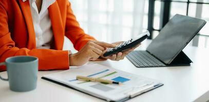 Businesswoman hands working with finances about cost and calculator and laptop with tablet, smartphone at office photo