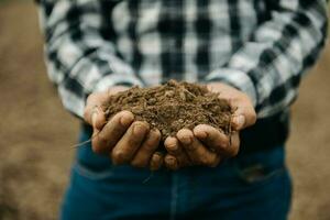 Oldman farmer holding soil in cupped hands photo