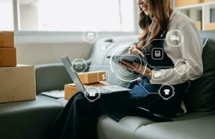 mano de mujer usando una computadora portátil, un teléfono inteligente y una tableta y escribiendo un cuaderno en la oficina de su negocio de compras en línea. en el hogar foto