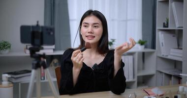 Beautiful young Asian woman blogger shows how to make up cosmetics at home photo