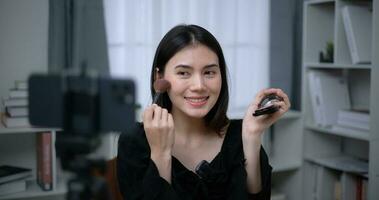 hermosa joven asiático mujer blogger muestra cómo a hacer arriba productos cosméticos a hogar foto