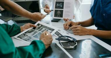 Medical team having a meeting with doctors in white lab coats and surgical scrubs seated at a table discussing a patients working online using computers in the medical industry photo